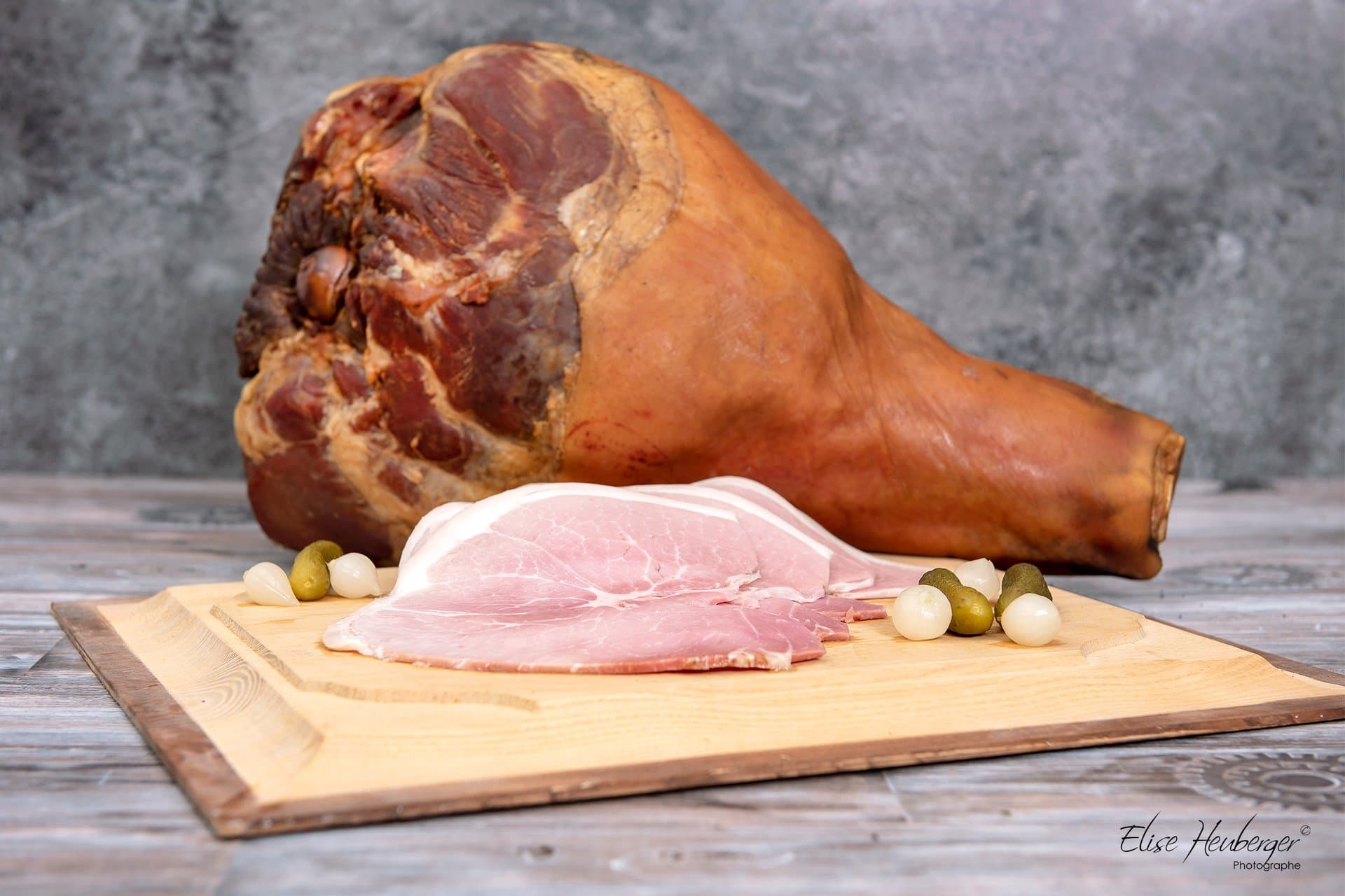 Jambon fumé entier et tranches de jambon sur planche en bois — Boucherie Jaquier
